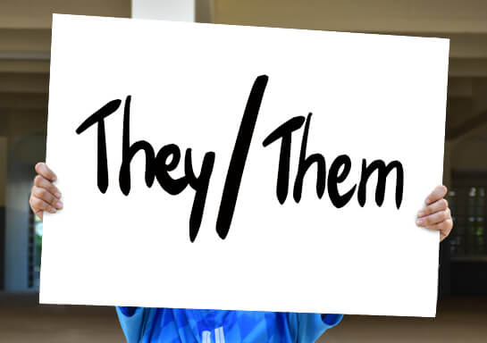Hands holding sign with They/Them written on it