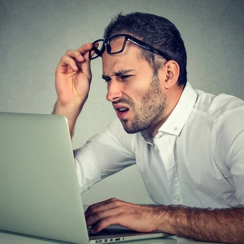 Confused man trying to read laptop screen