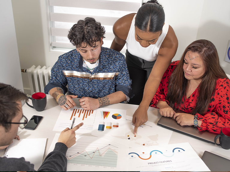 Group of people seated around desk reviewing project plans